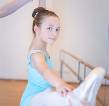 Ballett III Kurs – Mädchen in blauem Trikot bei Ballettübung mit Ballettstange
